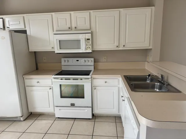 a kitchen with white cabinets and white appliances