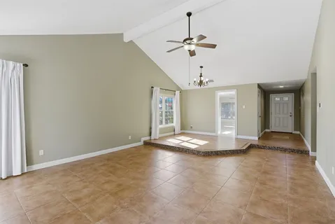 a view of empty room with window and chandelier fan
