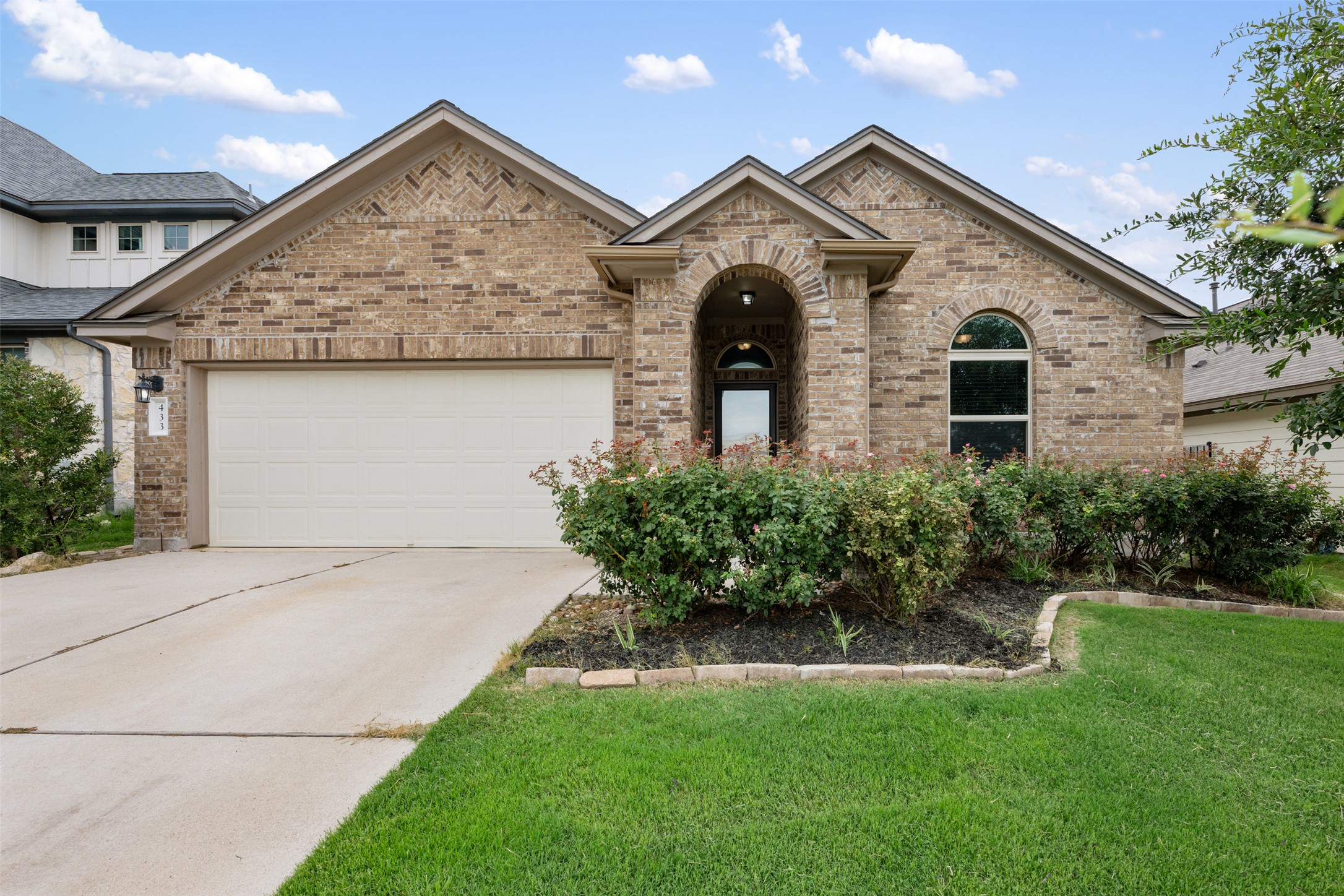 French provincial home featuring a garage, brick siding, a front lawn, and concrete driveway