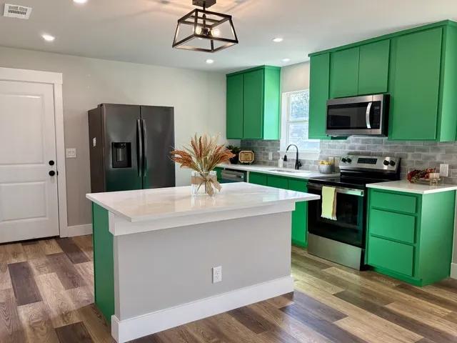 a kitchen with kitchen island granite countertop stainless steel appliances a sink cabinets and wooden floor