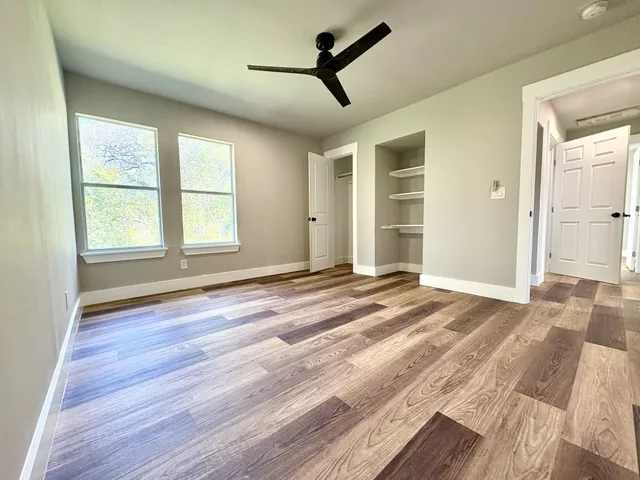 a view of an empty room with a window and wooden floor