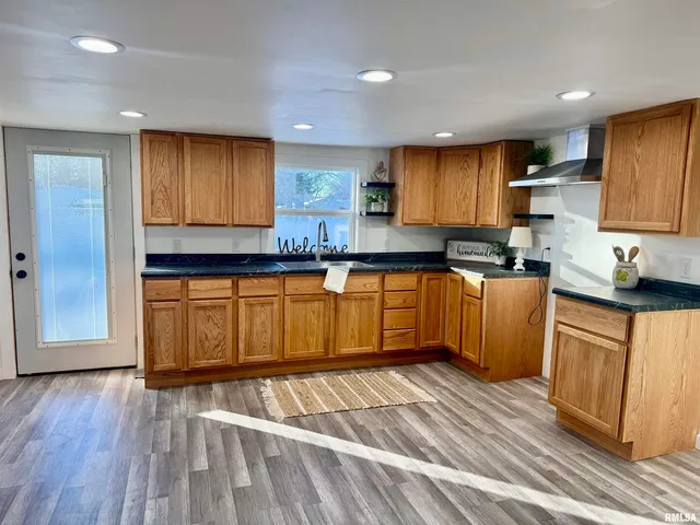 a kitchen with stainless steel appliances granite countertop wooden cabinets a sink a stove a refrigerator and dishwasher with wooden floor