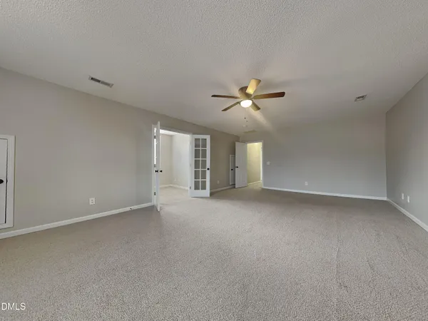 a view of an empty room with a chandelier fan