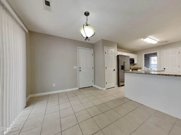 a view of an empty room and kitchen with granite countertop cabinets