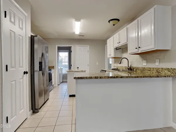 a large white kitchen with granite countertop a sink