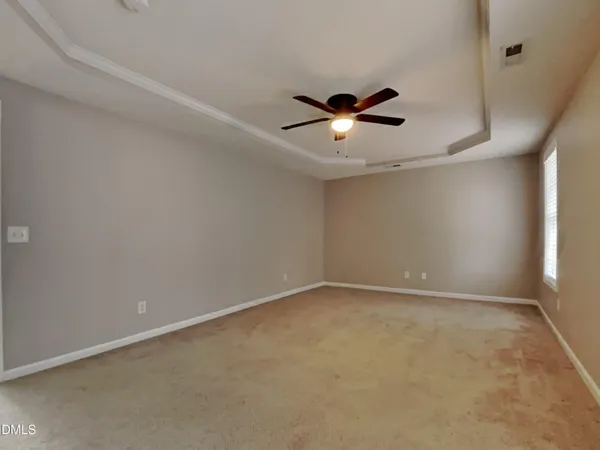 an empty room with a window and a fan