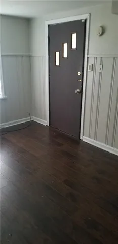 a view of an empty room with wooden floor and a bench