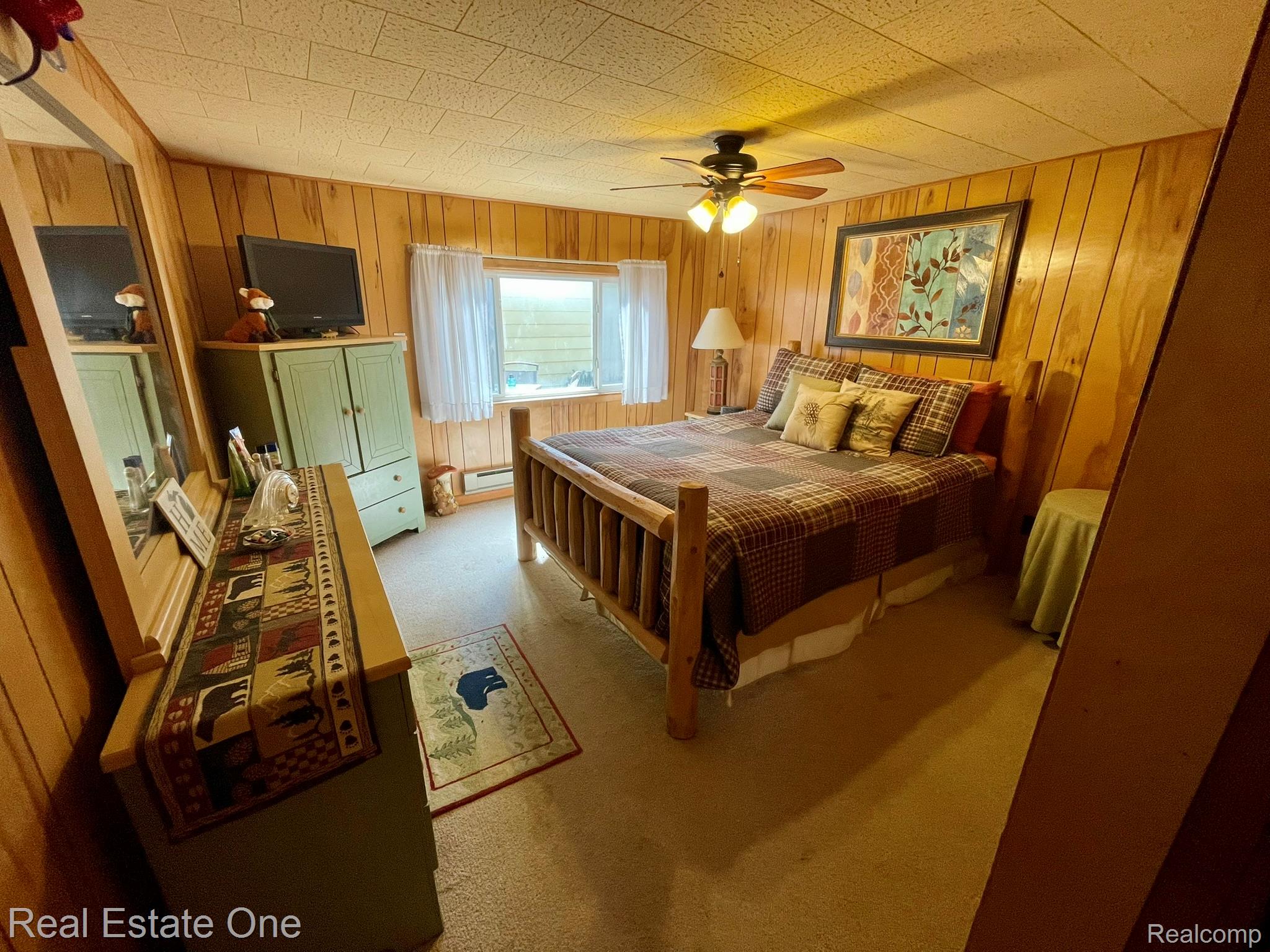 2596 Fox Road Lincoln, MI 48742 - Photo 15 of 54 Wood-paneled room featuring a ceiling fan with light fixture, carpeted flooring, and a window with white curtains