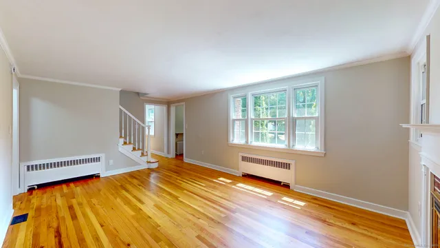 a view of a bedroom with wooden floor and a window