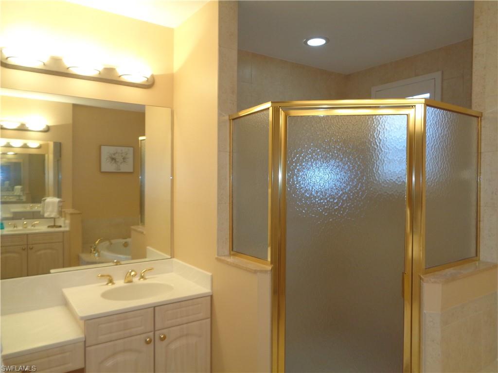 734 Regency Reserve Circle, Unit 2701 Naples, FL 34119 - Photo 23 of 37 a bathroom with a shower sink vanity and mirror