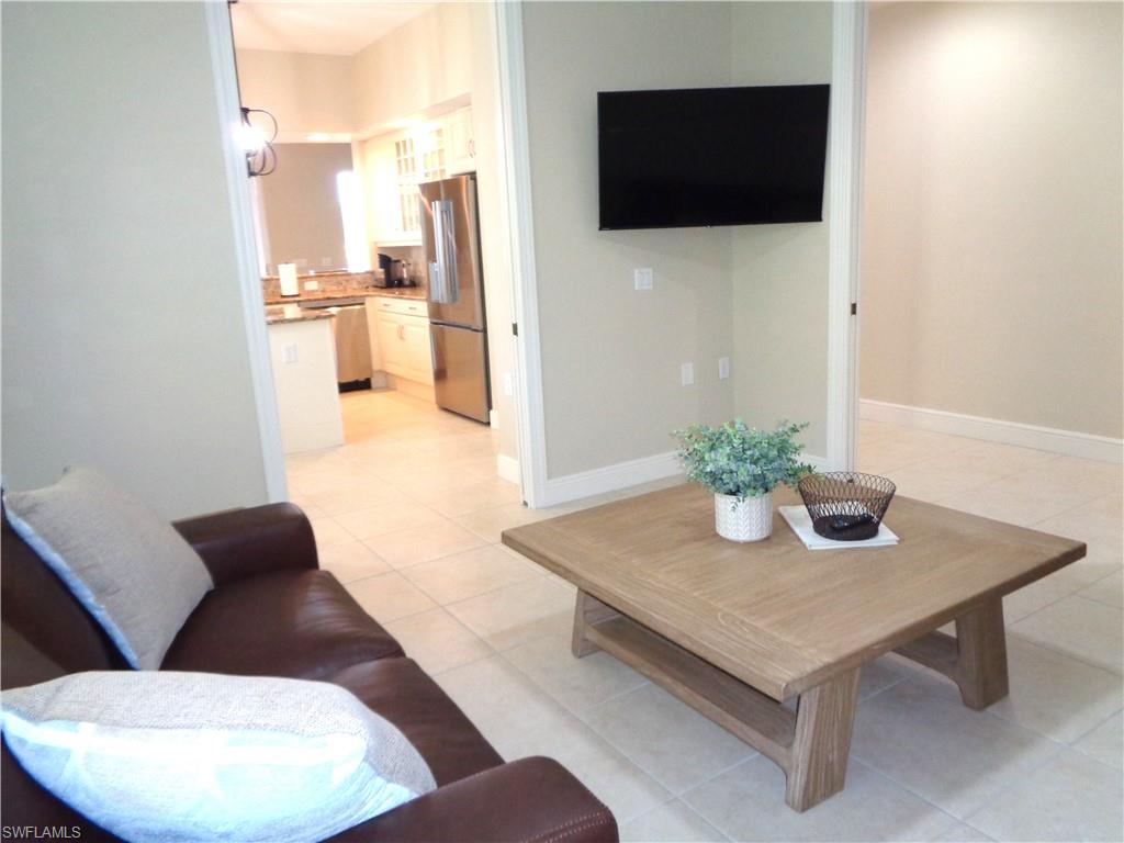 734 Regency Reserve Circle, Unit 2701 Naples, FL 34119 - Photo 6 of 37 a living room with furniture and a flat screen tv