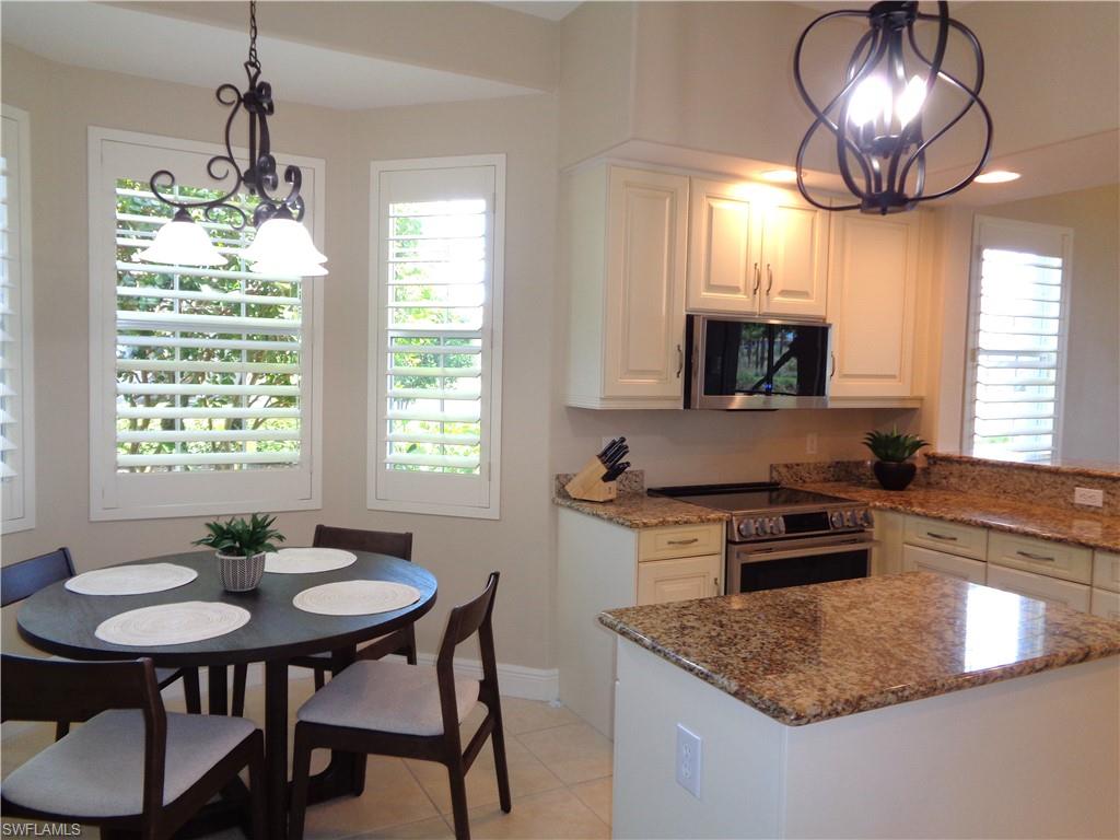 734 Regency Reserve Circle, Unit 2701 Naples, FL 34119 - Photo 9 of 37 a kitchen with stainless steel appliances granite countertop a stove a sink a microwave a dining table and chairs