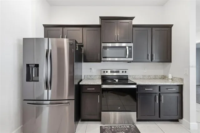 a kitchen with granite countertop a refrigerator and a stove top oven