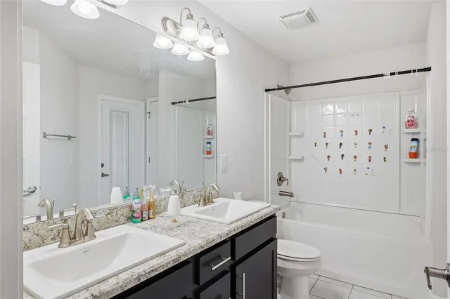 a bathroom with a granite countertop sink a toilet a mirror a shower and vanity