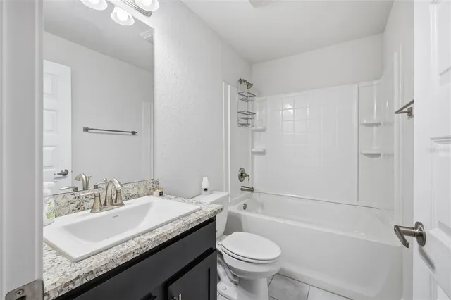 a bathroom with a granite countertop sink a toilet a mirror a bathtub and shower