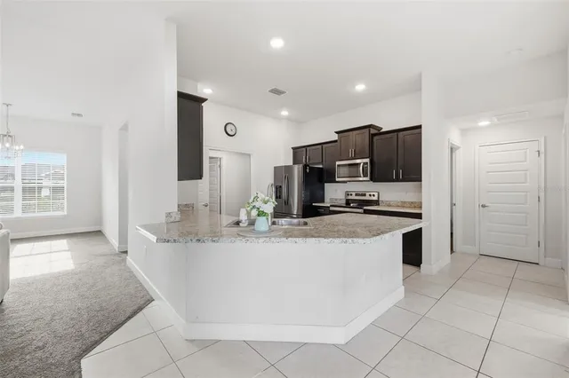 a view of kitchen with stainless steel appliances granite countertop a sink and a refrigerator