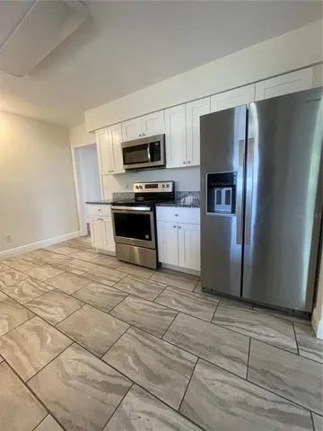 a kitchen with stainless steel appliances granite countertop a refrigerator a stove top oven a sink and dishwasher