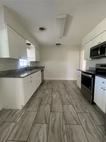 a kitchen with granite countertop a sink cabinets and stainless steel appliances