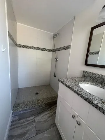 a bathroom with a granite countertop sink a mirror and shower
