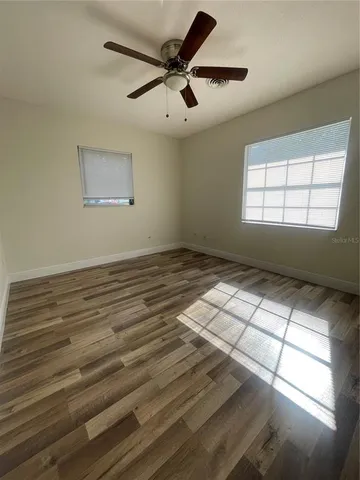 a view of empty room with window and ceiling fan