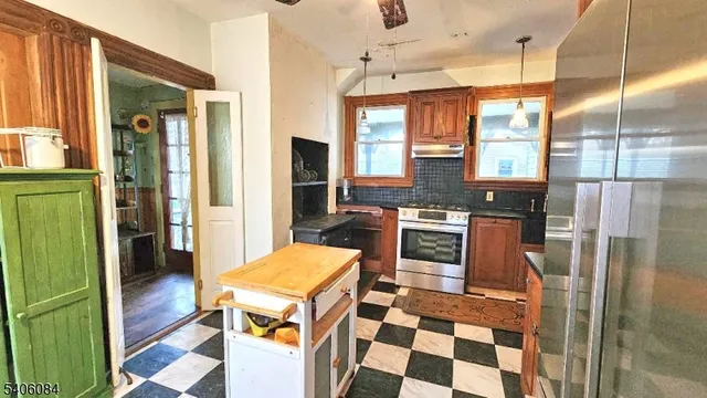 a kitchen with stainless steel appliances granite countertop a refrigerator a stove and a sink with wooden floor