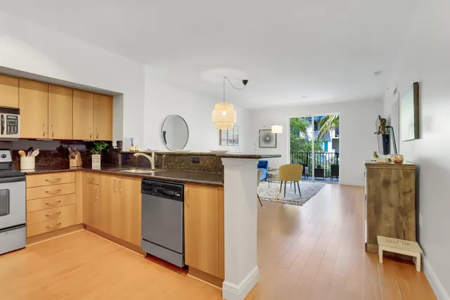 a kitchen with stainless steel appliances granite countertop a stove a sink a refrigerator and a dining table with wooden floor