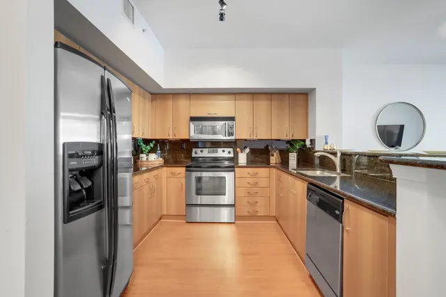 a kitchen with granite countertop a refrigerator stove top oven and sink