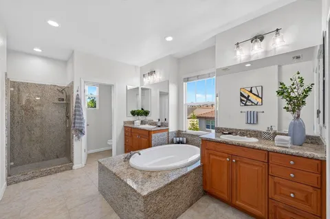 a spacious bathroom with a granite countertop sink a mirror a bathtub and shower