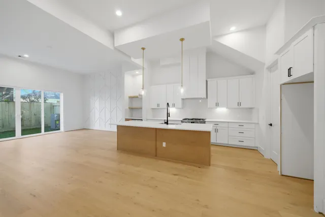 a large white kitchen with kitchen island a sink stainless steel appliances and cabinets