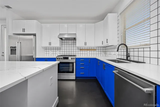 a kitchen with stainless steel appliances a sink dishwasher a refrigerator oven a stove and a dining table with wooden floor