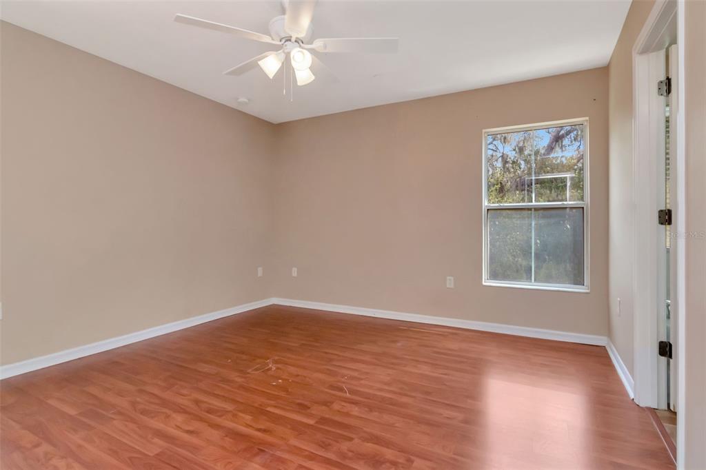 6952 Marble Fawn Place Riverview, FL 33578 - Photo 24 of 42 an empty room with wooden floor chandelier fan and windows