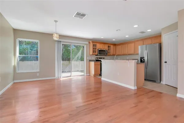 a view of a kitchen with a refrigerator wooden floor and a window
