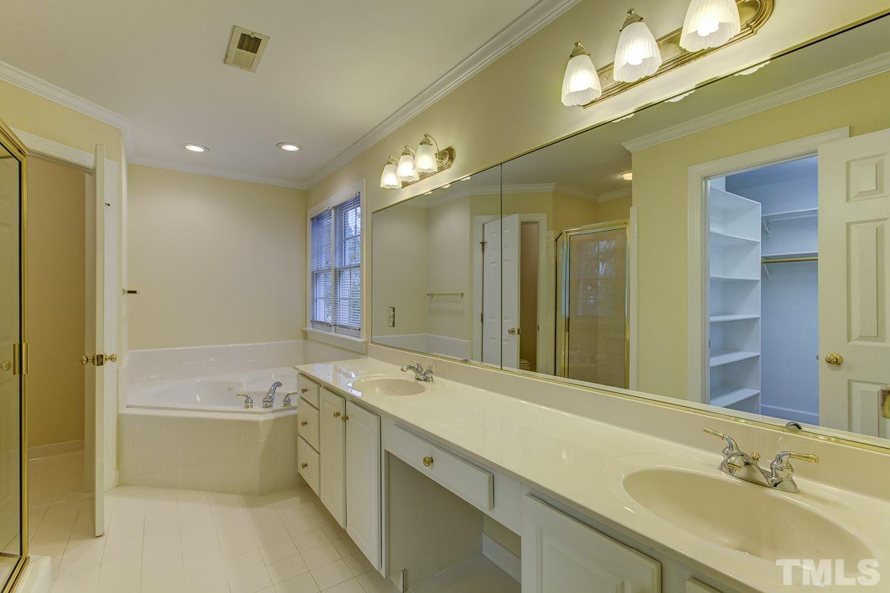 6805 Wilderness Road Raleigh, NC 27613 - Photo 14 of 25 a bathroom with a granite countertop sink a large mirror and a bathtub
