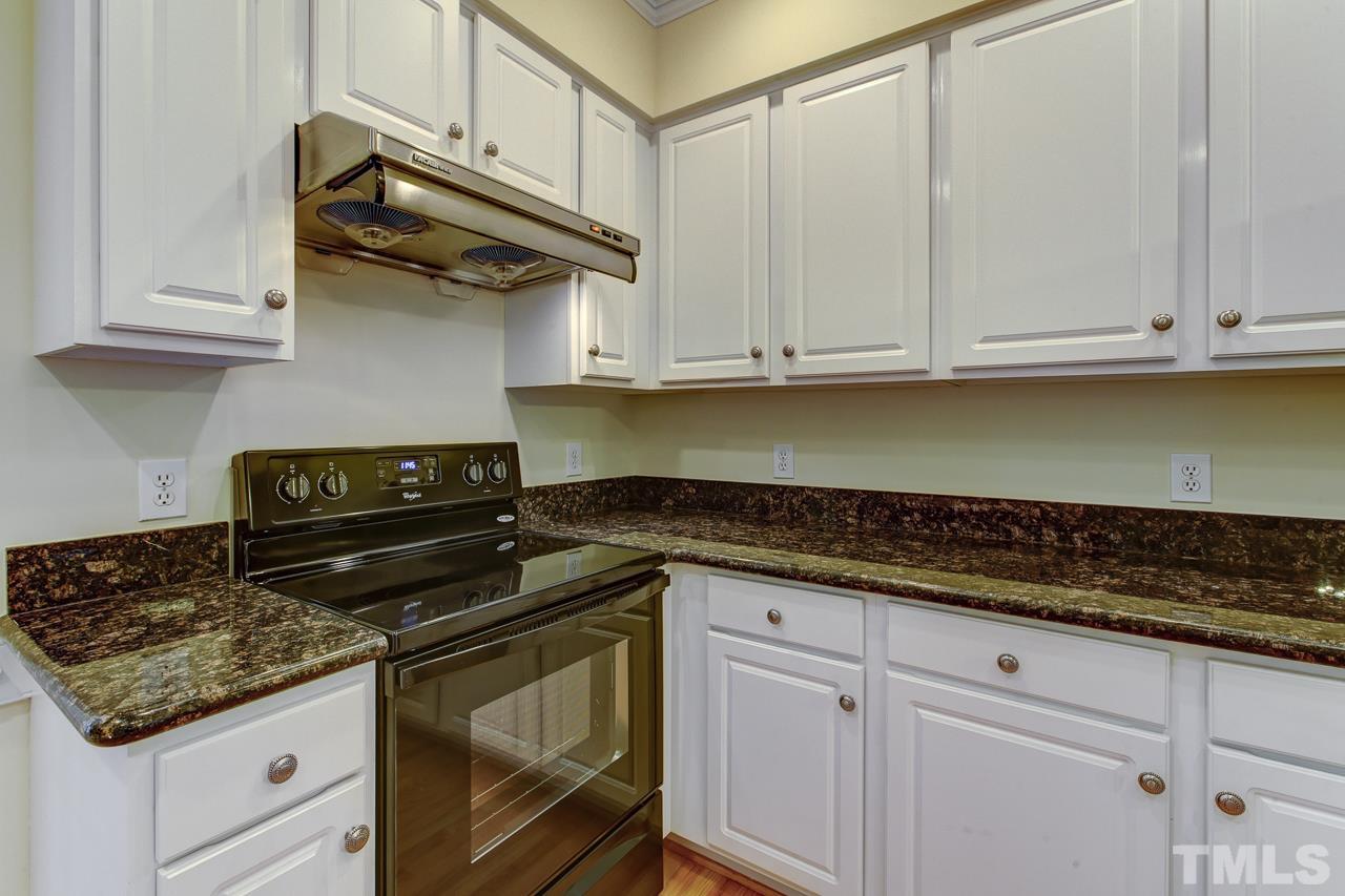 6805 Wilderness Road Raleigh, NC 27613 - Photo 9 of 25 a kitchen with granite countertop white cabinets and a stove top oven