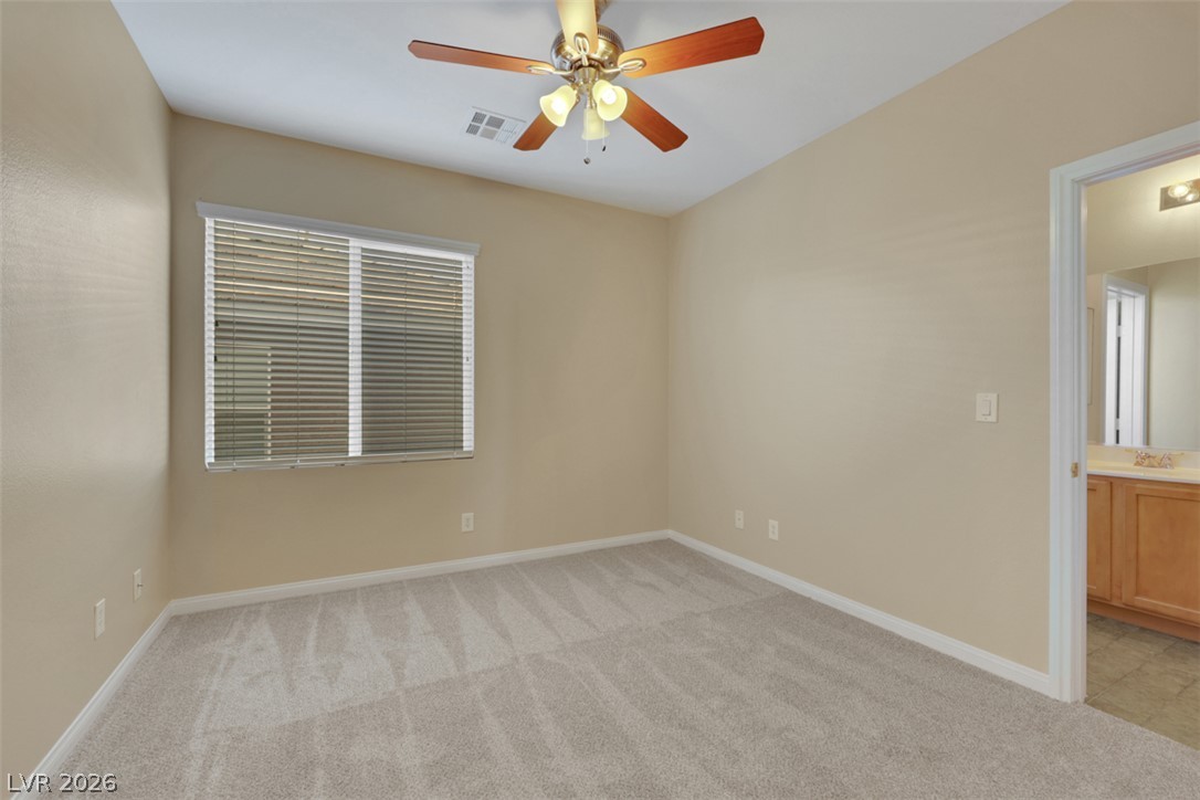 10328 Hawk Ravine Street Las Vegas, NV 89178 - Photo 28 of 55 A quiet bedroom offers plush carpeting and a bright window with a ceiling fan for comfort.