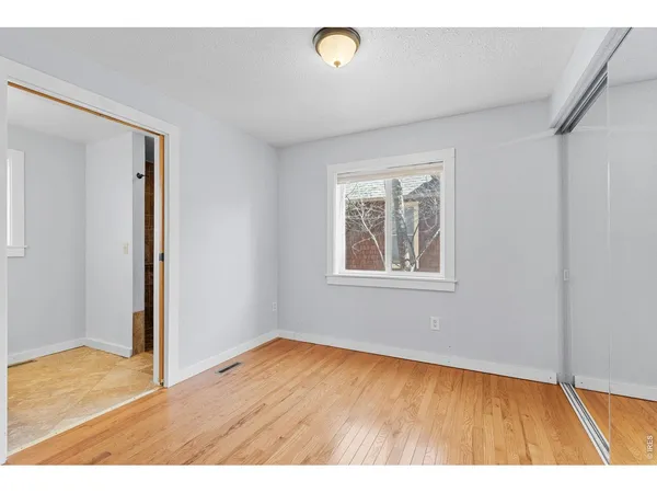 a view of an empty room with window and wooden floor