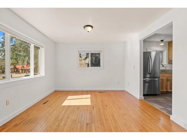 a view of an empty room with a window and wooden floor
