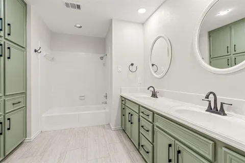a bathroom with a double vanity sink mirror and bathtub