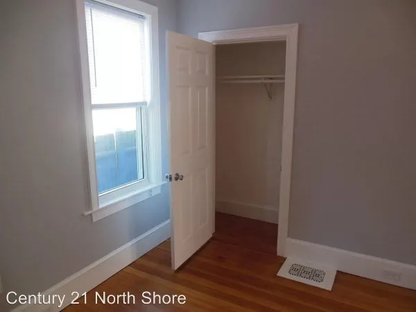 a view of an empty room with wooden floor and closet