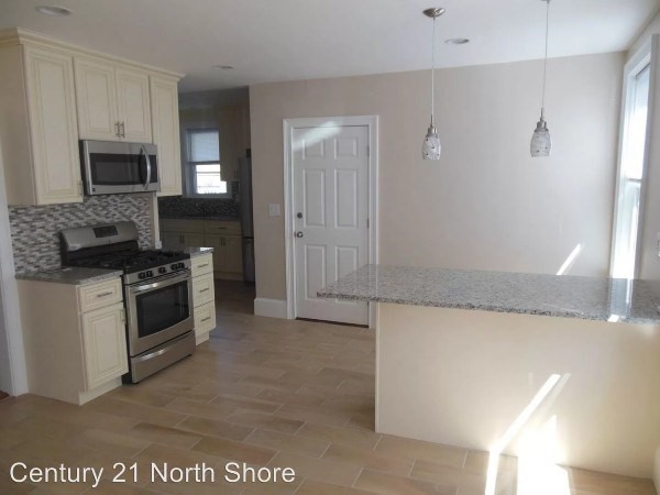 5 Pearl Street, Unit 1 Salem, MA 01970 - Photo 7 of 14 a kitchen with white cabinets and stainless steel appliances