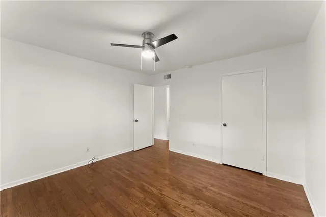 an empty room with wooden floor and ceiling fan