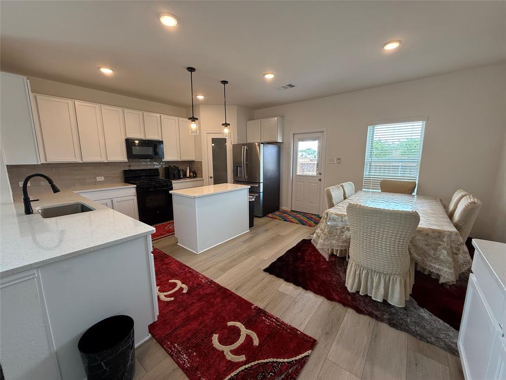 2006 Placerville Street Forney, TX 75126 - Photo 14 of 35 Kitchen featuring white cabinetry, light-toned countertops, tile backsplash, and wood-finish flooring