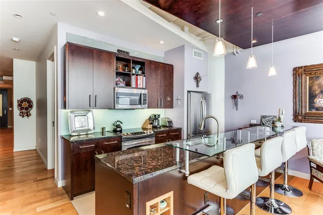 a kitchen with stainless steel appliances granite countertop a sink and a refrigerator