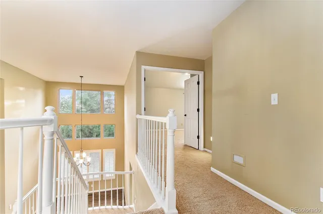 a view of an empty room with chandelier fan and windows