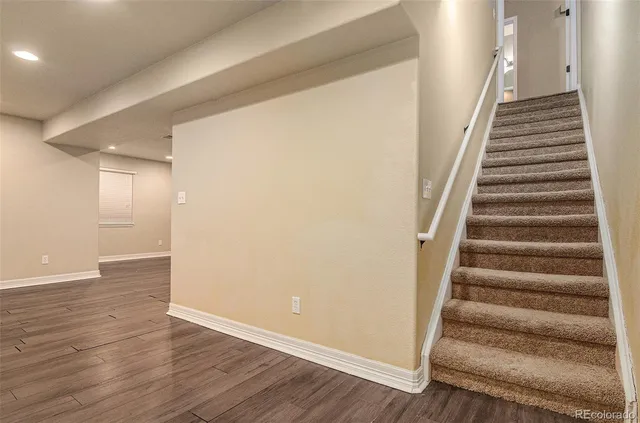 a view of empty room with wooden floor and kitchen