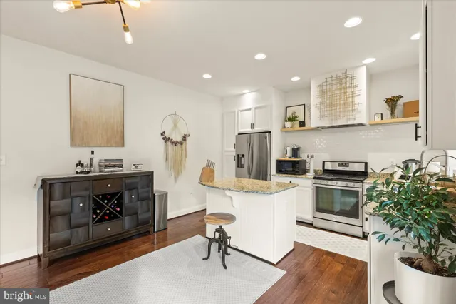 a kitchen with stainless steel appliances granite countertop a sink stove refrigerator and cabinets