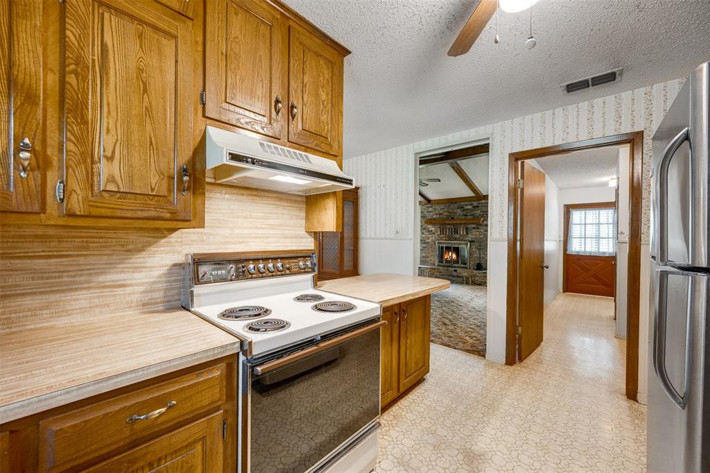 8798 Hill N Dale Road Tyler, TX 75709 - Photo 12 of 31 Kitchen featuring wood cabinetry, laminate countertops, and a built-in range with overhead vent hood