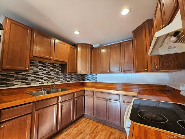 a kitchen with stainless steel appliances granite countertop wooden cabinets a sink and dishwasher a stove with wooden floor