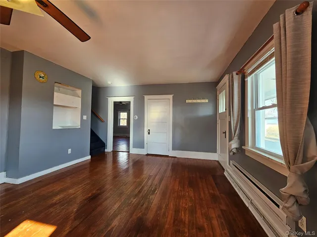 a view of an empty room with wooden floor and a window