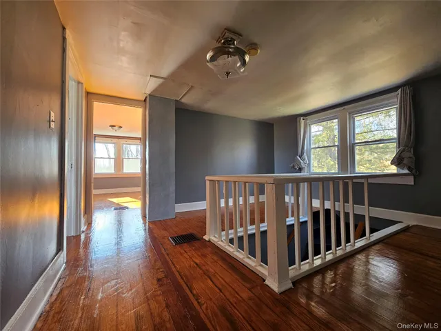 a view of a hallway with wooden floor and stairs
